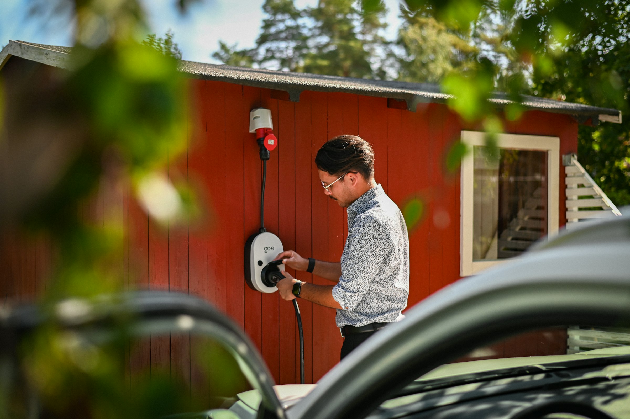 Persoon laadt een elektrische wagen thuis op aan een wandlader